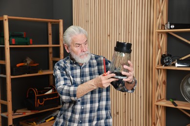 Photo of Relaxing hobby. Senior man repairing blender with screwdriver in workshop