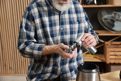 Photo of Relaxing hobby. Senior man repairing meat grinder in workshop, closeup