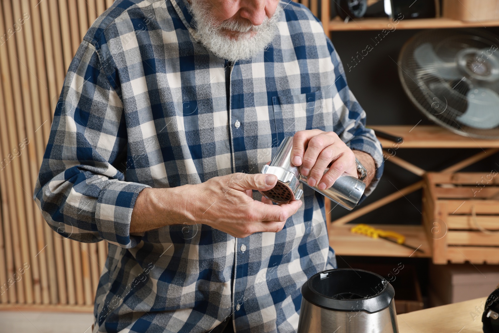 Photo of Relaxing hobby. Senior man repairing meat grinder in workshop, closeup