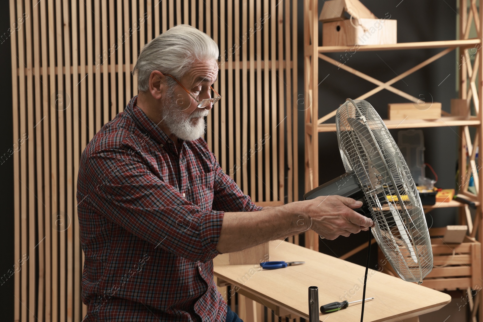 Photo of Relaxing hobby. Senior man repairing fan in workshop