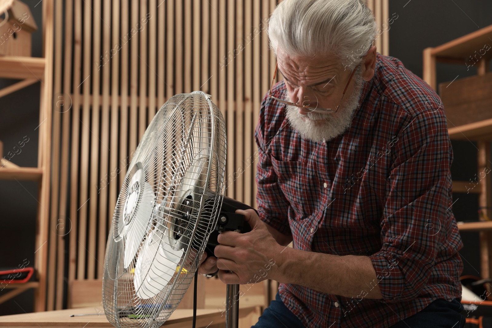 Photo of Relaxing hobby. Senior man repairing fan in workshop