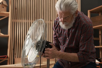 Photo of Relaxing hobby. Senior man repairing fan in workshop