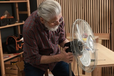 Photo of Relaxing hobby. Senior man repairing fan in workshop