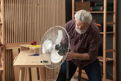 Photo of Relaxing hobby. Senior man repairing fan in workshop