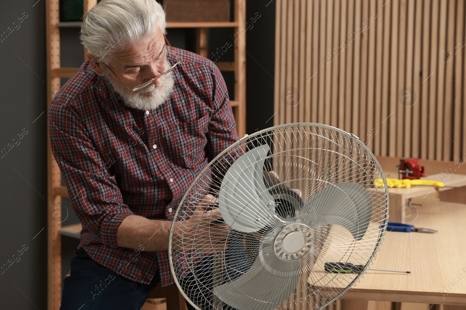 Photo of Relaxing hobby. Senior man repairing fan in workshop