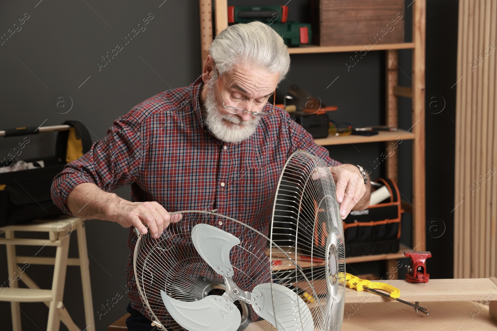 Photo of Relaxing hobby. Senior man repairing fan in workshop