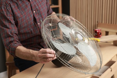 Photo of Relaxing hobby. Senior man repairing fan in workshop, closeup