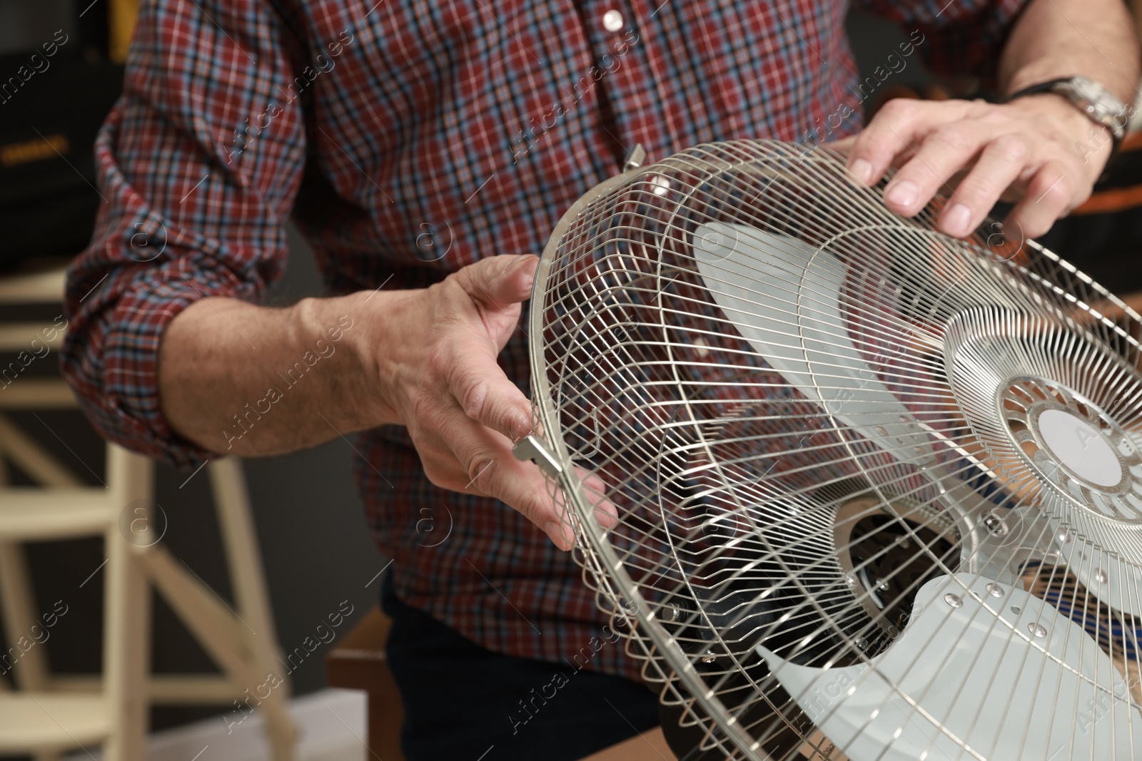 Photo of Relaxing hobby. Senior man repairing fan in workshop, closeup