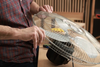 Photo of Relaxing hobby. Senior man repairing fan in workshop, closeup