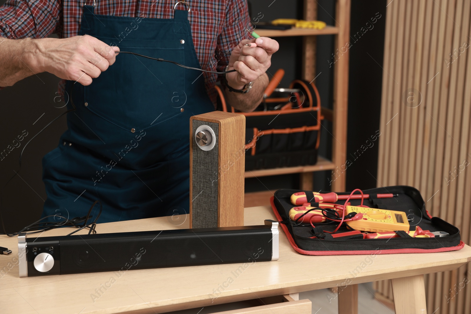 Photo of Relaxing hobby. Senior man testing portable bluetooth speaker in workshop, closeup