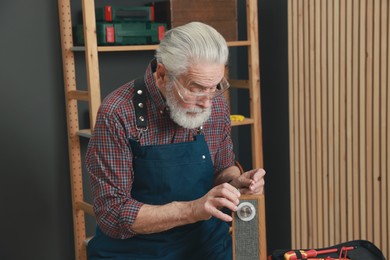 Photo of Relaxing hobby. Senior man testing portable bluetooth speaker in workshop