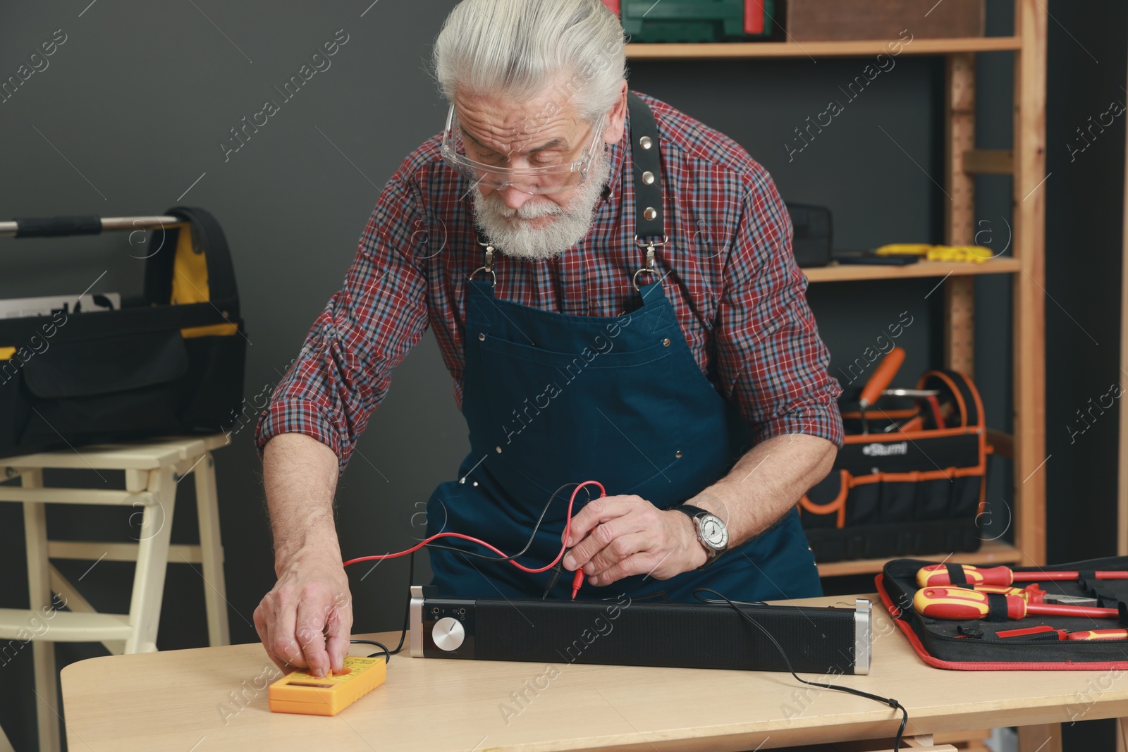 Photo of Relaxing hobby. Senior man testing soundbar with multimeter in workshop