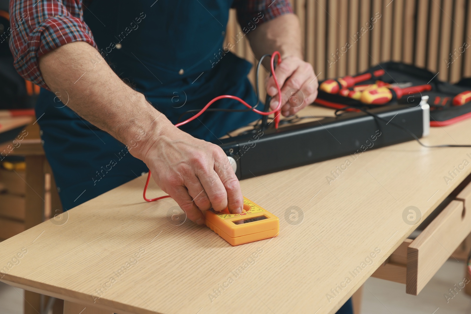 Photo of Relaxing hobby. Senior man testing soundbar with multimeter in workshop, closeup