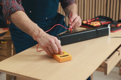 Photo of Relaxing hobby. Senior man testing soundbar with multimeter in workshop, closeup