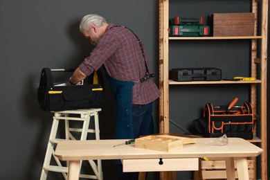 Relaxing hobby. Senior man with tool bag in workshop