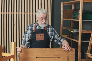 Photo of Relaxing hobby. Senior man measuring wooden plank with tape in workshop