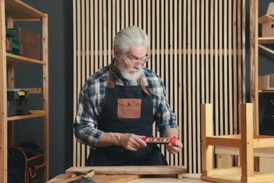 Photo of Relaxing hobby. Senior man with level tool in workshop