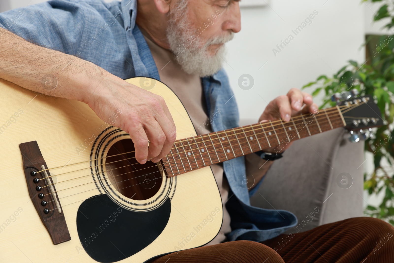 Photo of Relaxing hobby. Senior man playing guitar at home, selective focus