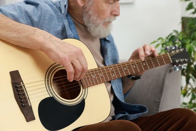 Photo of Relaxing hobby. Senior man playing guitar at home, selective focus