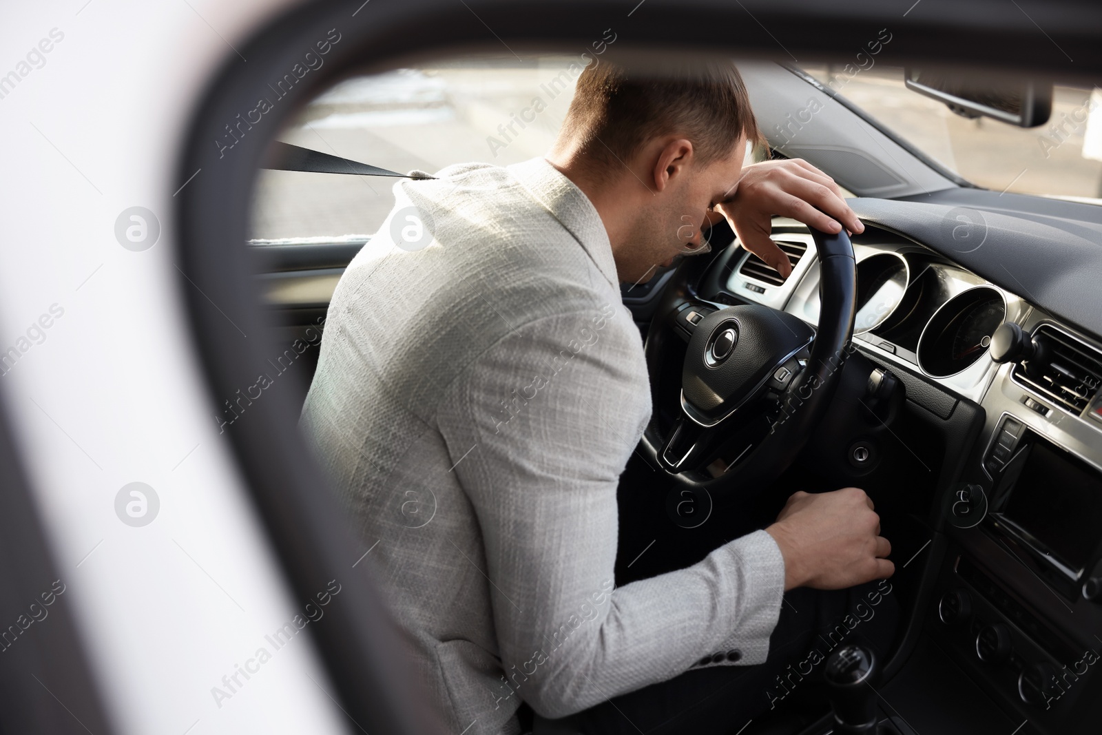 Photo of Tired driver sleeping on steering wheel in car, view from window