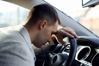 Photo of Tired driver sleeping on steering wheel in car