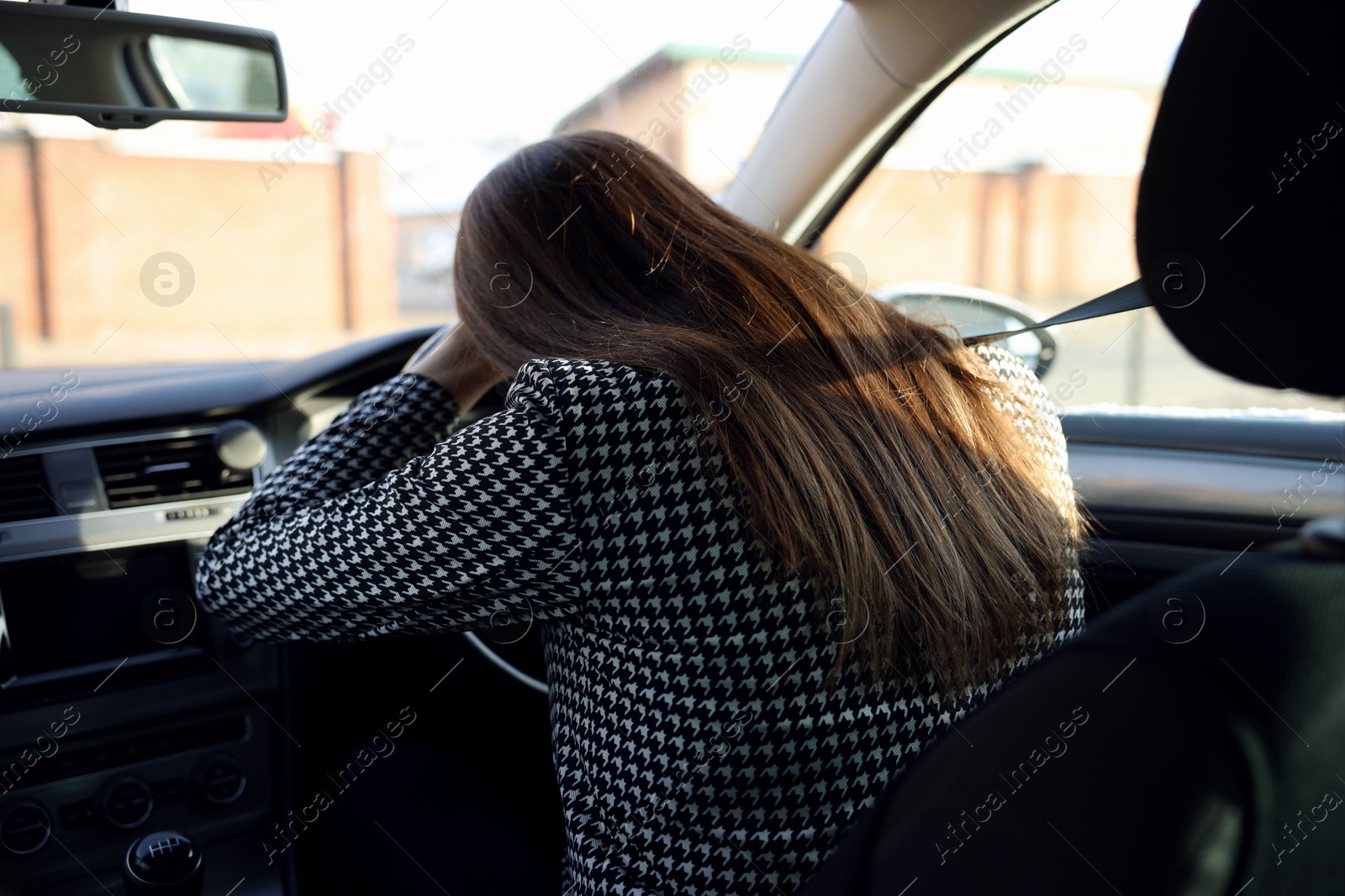 Photo of Tired driver sleeping on steering wheel in car, view from inside