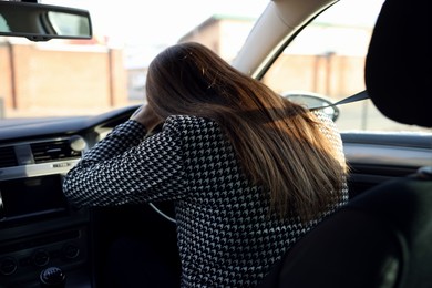 Photo of Tired driver sleeping on steering wheel in car, view from inside