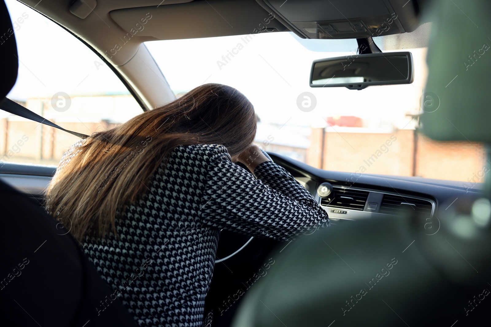 Photo of Tired driver sleeping on steering wheel in car, view from inside