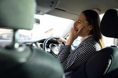 Photo of Sleepy driver yawning in her modern car, view from inside