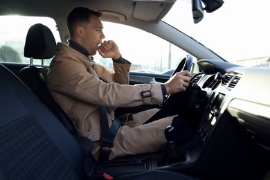 Photo of Sleepy driver yawning in his modern car