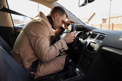 Photo of Tired driver sleeping on steering wheel in car