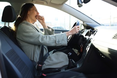 Photo of Sleepy driver yawning in her modern car