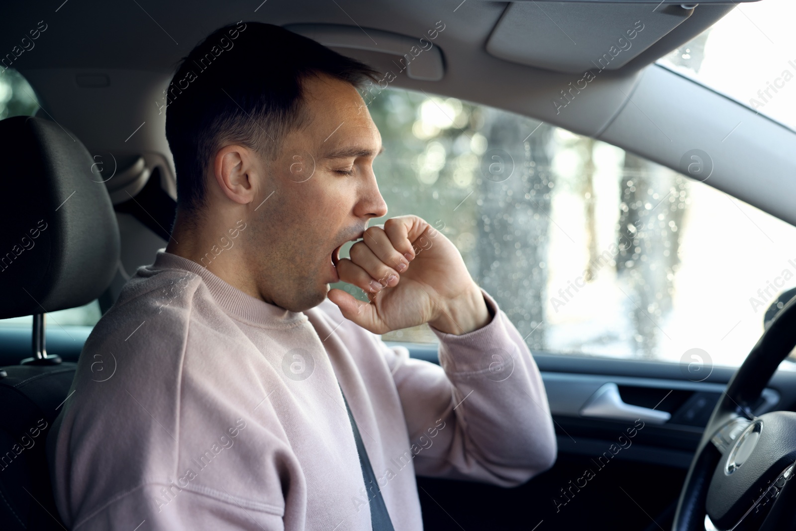 Photo of Sleepy driver yawning in his modern car