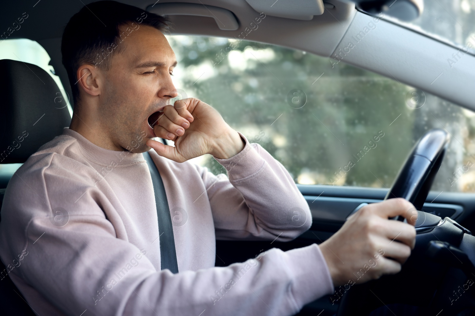 Photo of Sleepy driver yawning in his modern car