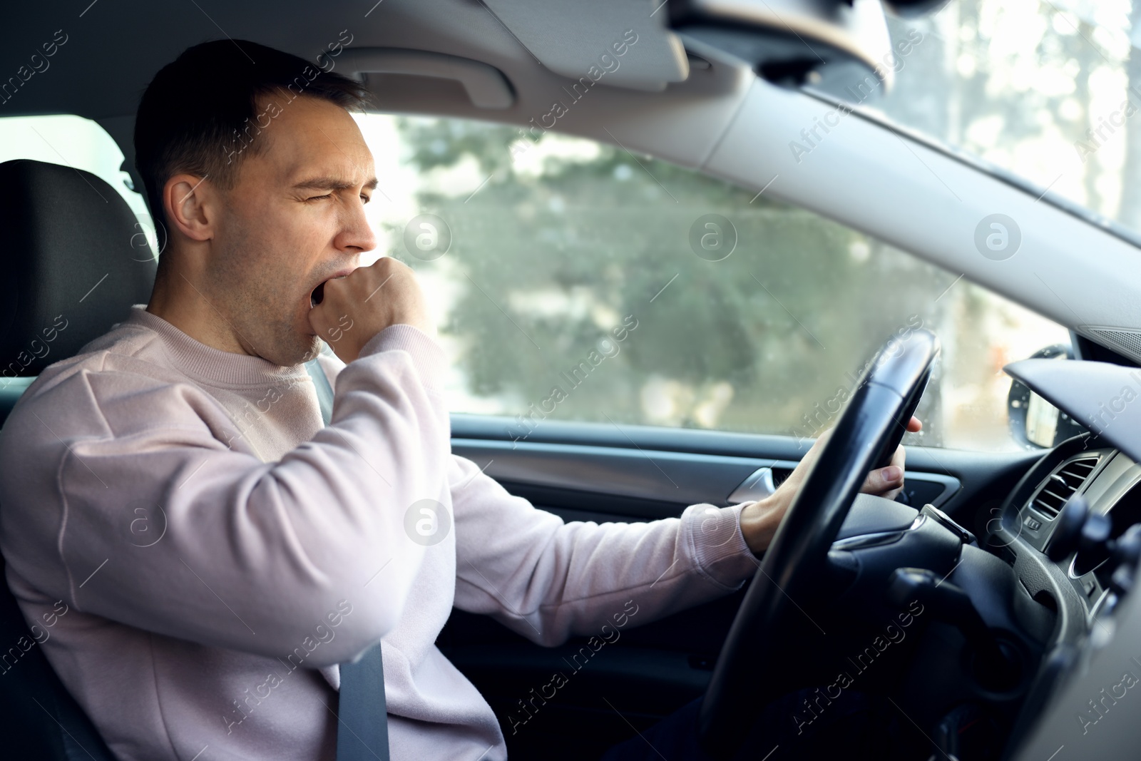 Photo of Sleepy driver yawning in his modern car