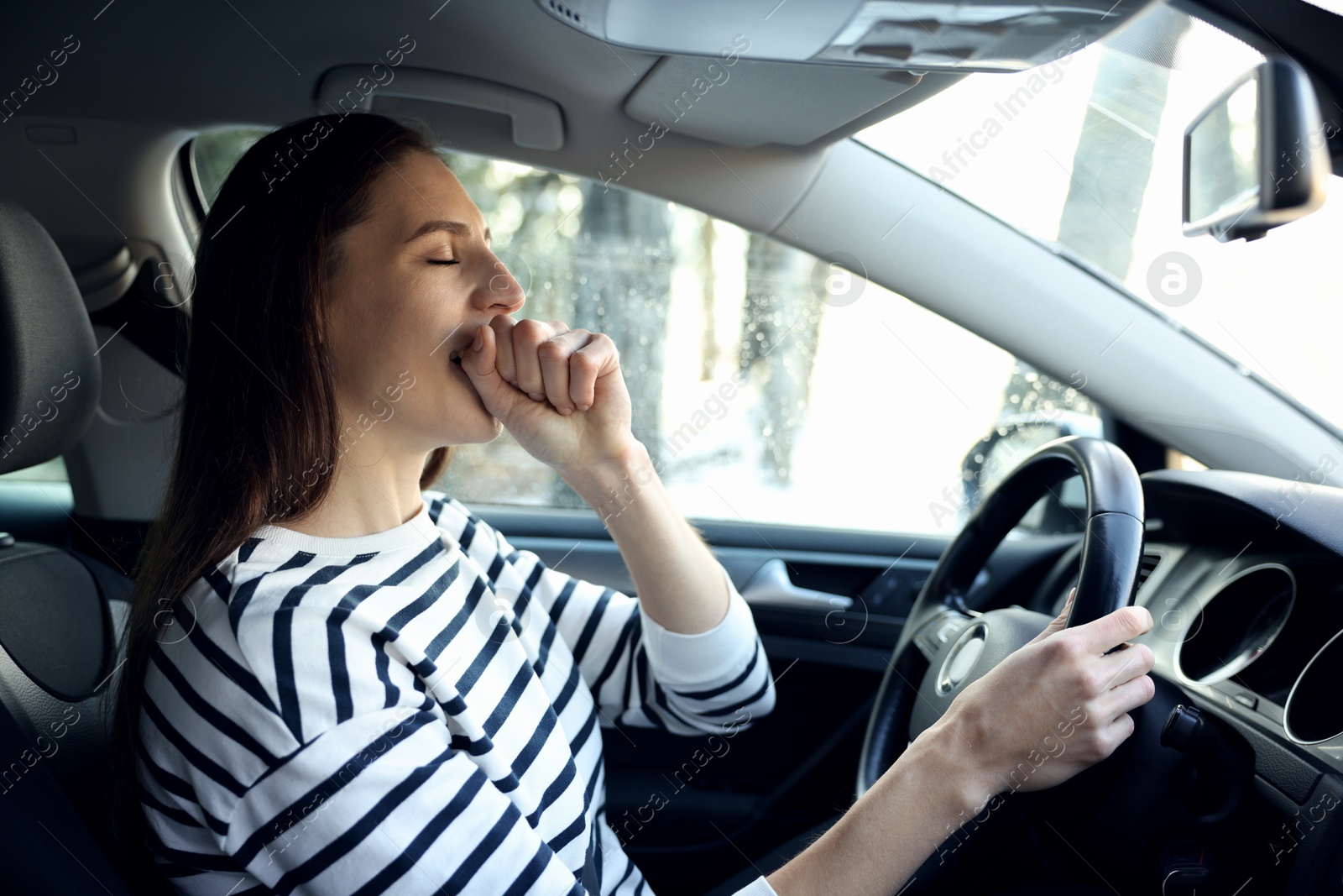 Photo of Sleepy driver yawning in her modern car