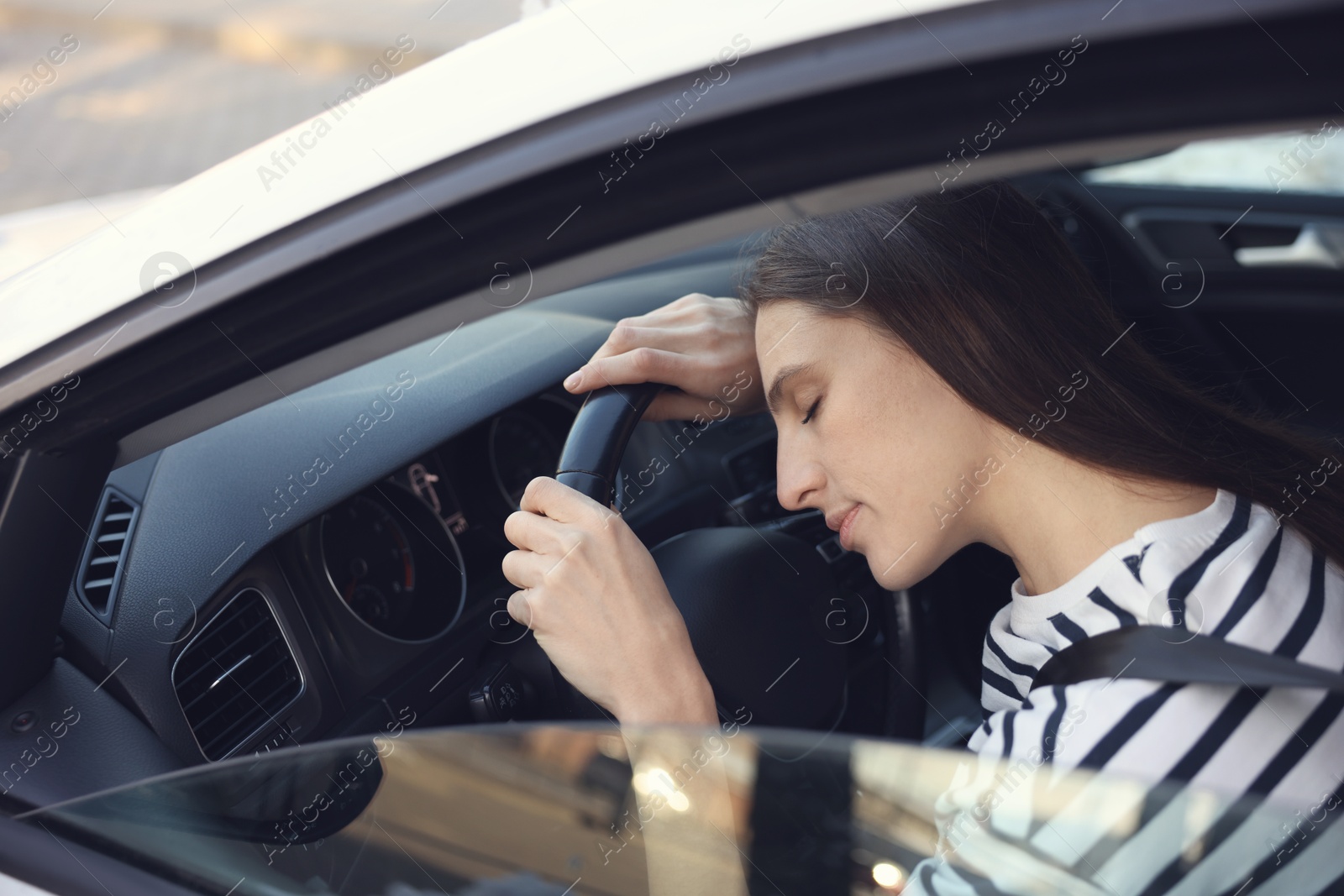 Photo of Tired driver sleeping on steering wheel in car, view from outside