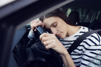 Photo of Tired driver sleeping on steering wheel in car, view from outside