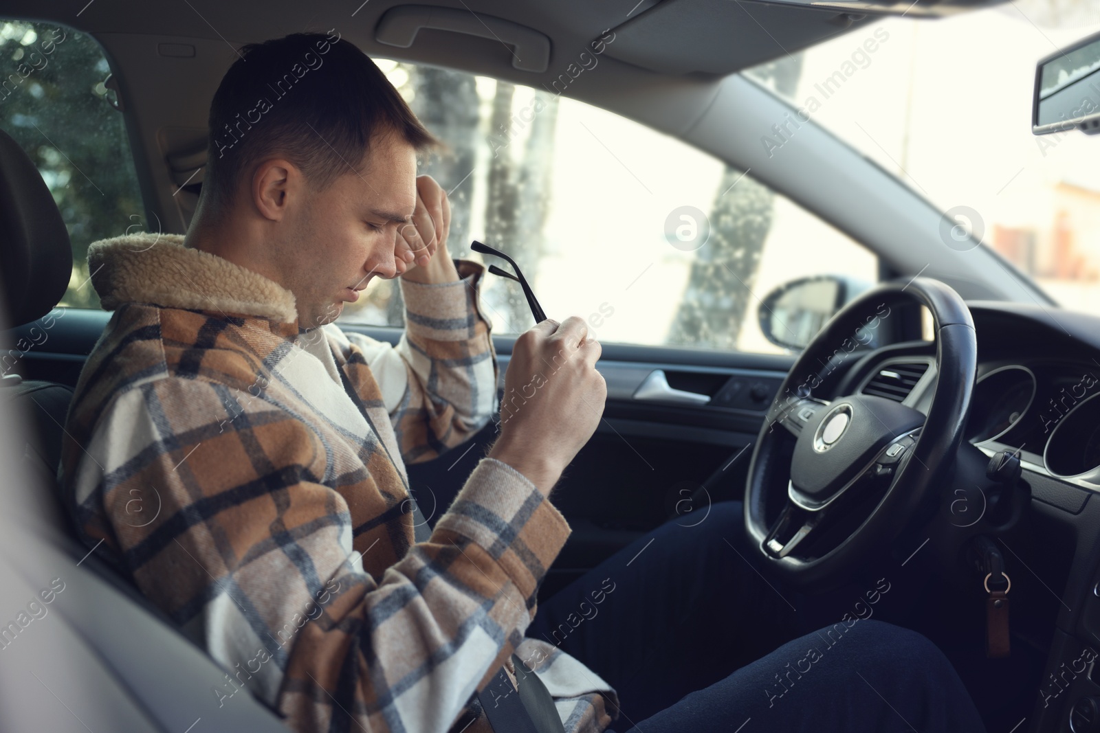 Photo of Sleepy driver with glasses in his modern car