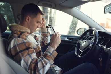 Photo of Sleepy driver with glasses in his modern car