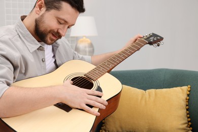 Photo of Relaxing hobby. Man playing guitar on sofa at home