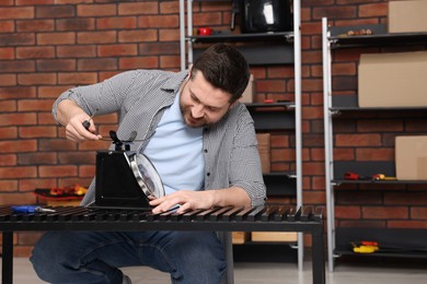 Photo of Relaxing hobby. Man repairing mechanical kitchen scale with screwdriver in workshop