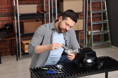 Photo of Relaxing hobby. Man repairing electric meat grinder in workshop