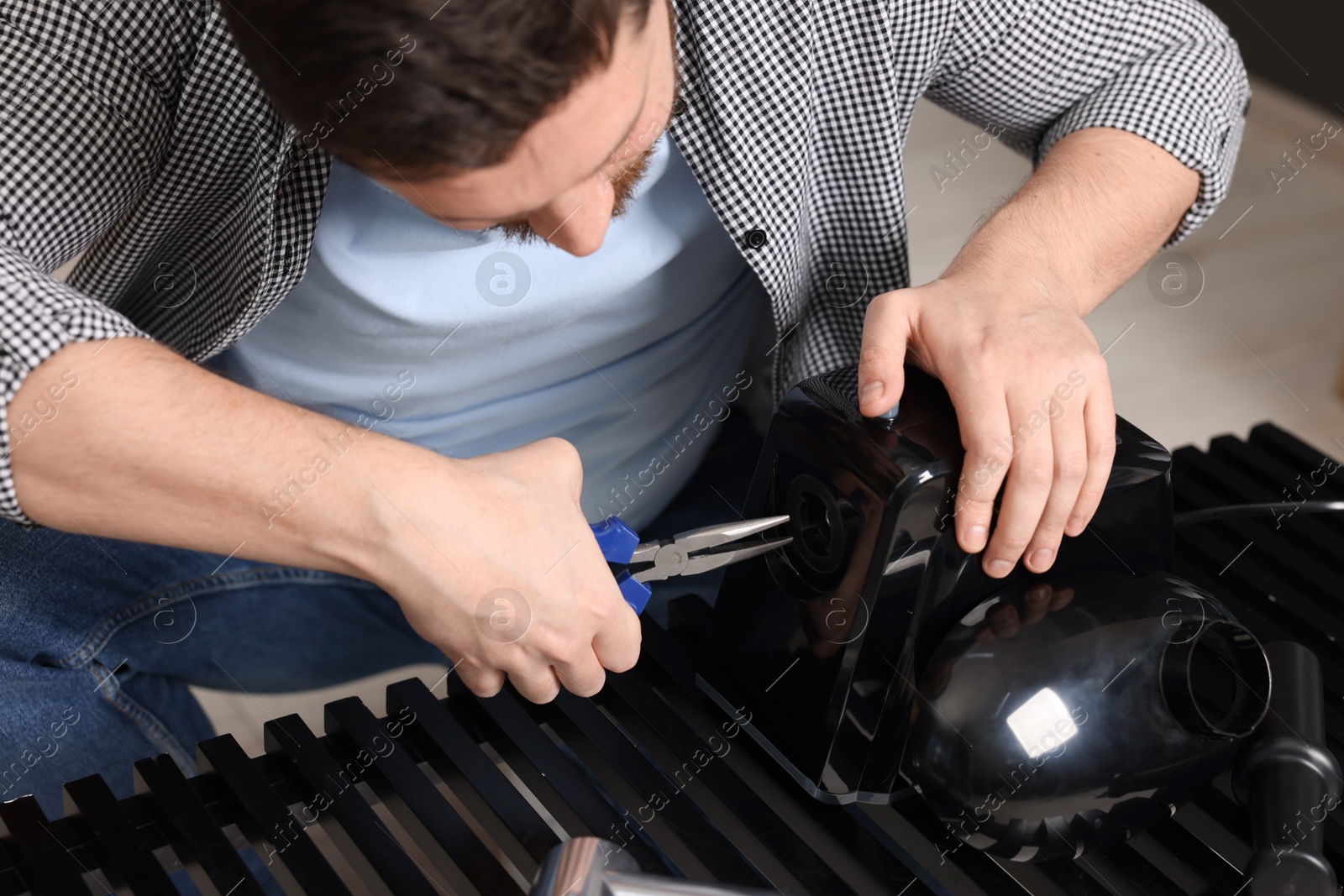 Photo of Relaxing hobby. Man repairing electric meat grinder indoors