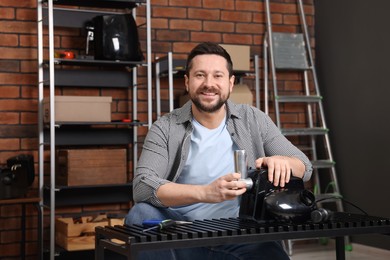 Photo of Relaxing hobby. Smiling man repairing electric meat grinder in workshop