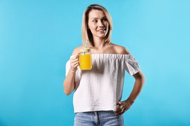 Photo of Woman with mason jar of orange juice on light blue background. Refreshing drink