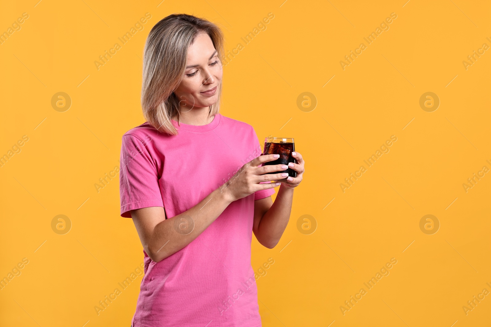 Photo of Woman with glass of refreshing soda drink on orange background, space for text