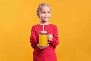 Girl with mason jar of juice on orange background, space for text. Refreshing drink