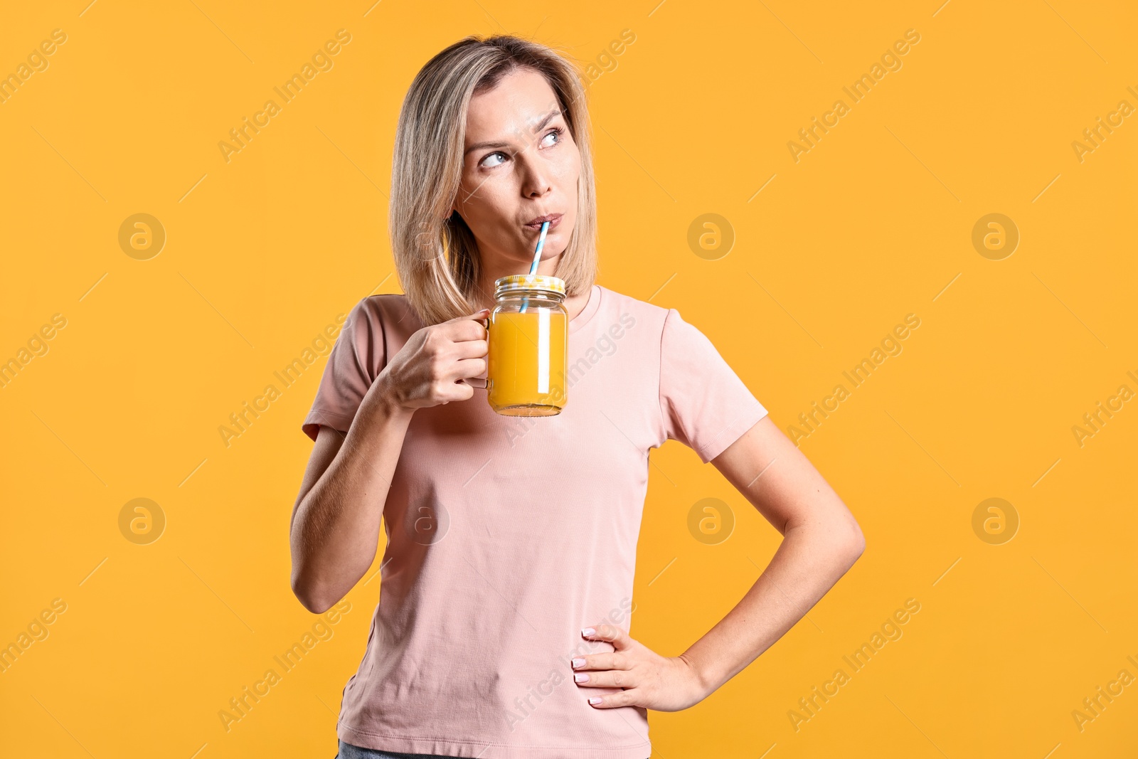 Photo of Woman with mason jar of juice on orange background. Refreshing drink