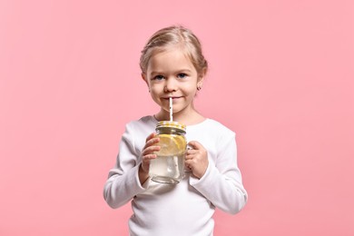 Girl drinking tasty lemonade on pink background. Refreshing drink